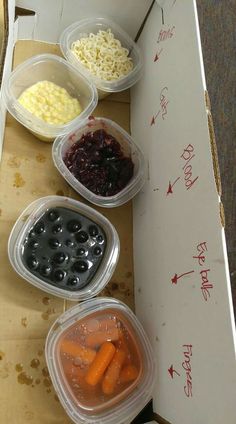 four plastic containers filled with food sitting on top of a cardboard box next to another container