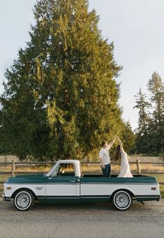 a bride and groom standing in the back of a pickup truck