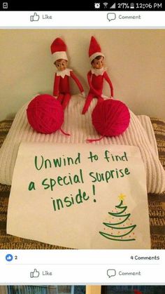 two elfs sitting on top of a bed next to a sign that says, unwind to find a special surprise inside