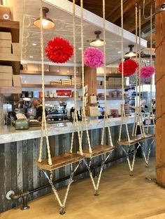 several wooden benches hanging from the ceiling in a restaurant with pink pom - poms