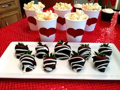 chocolate covered strawberries are arranged on a white platter with red and black hearts