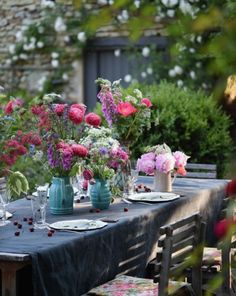 the table is set with flowers in vases and plates