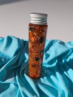 a jar filled with glitter sitting on top of a blue cloth