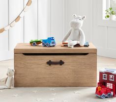 a teddy bear sitting on top of a wooden box next to toy cars and a firetruck