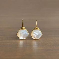 Lustrous mother of pearl from Mexico glistens from within their expertly crafted bezels in this divine pair. 

18k yellow gold 
Mother of Pearl, 8.28ctw, 14mm x 12mm (9/16" x 1/2")
Earrings hang 7/8" from the ear 
Each earring weighs 1.9g Elegant Hexagon Earrings For Gift, Elegant Gold Hexagon Earrings, Yellow Gold Mother Of Pearl Earrings, Yellow Gold Mother Of Pearl Round Earrings, Elegant White Hexagon Jewelry, Gold Octagon Earrings For Wedding, Luxury Gold Octagon Earrings, Luxury Octagon Gemstone Earrings, Gold Octagon Wedding Earrings