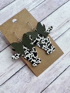 the earrings are decorated with black and white cow print fabric, leaves and spots on them