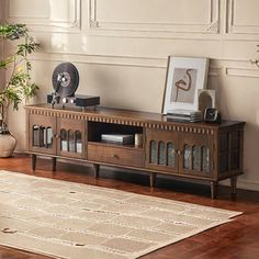 a living room with a large rug and a wooden entertainment center in front of a window