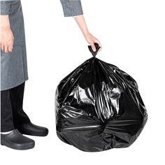 a person holding a black trash bag in one hand and another with shoes on the other