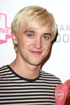 a man with blonde hair standing next to a woman wearing a black and white striped shirt