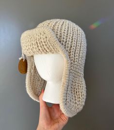 This handmade chunky knit trapper hat is perfect for colder temperatures, with ear flaps and thick yarn to keep your head and ears nice and toasty!  Off-white acrylic yarn used in a rib knit stitch. The hat also covers most of the neck, see picture. Size: medium/large Main circumference: 23 inches Knit Trapper Hat, Adjustable Cozy Cap Bonnet, Winter Adjustable Bonnet In Acrylic Yarn, Warm Bonnet With Ear Flaps, Adjustable Knitted Beanie With Ear Flaps, Cozy Adjustable Hats With Ear Flaps, Winter Brimmed Hat In Acrylic Yarn, Warm Beige Acrylic Hats, White Acrylic Yarn Beanie For Winter