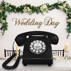 an old fashioned phone sitting on top of a table next to candles and greenery