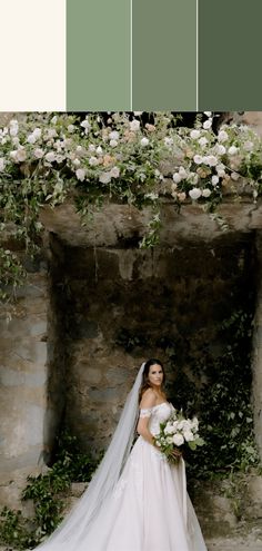 a bride standing in front of a stone wall with flowers and greenery on it