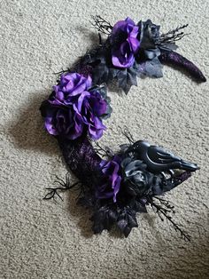 purple flowers and black feathers are on the floor next to a pair of scissors,