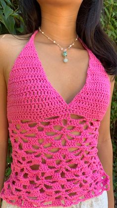 a woman wearing a bright pink crocheted top