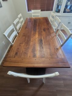 a wooden table with white chairs around it