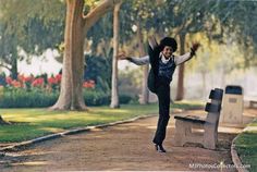 a woman jumping in the air near a park bench