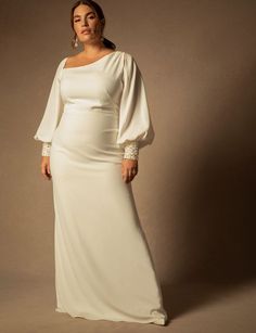 a woman in a long white dress posing for the camera with her hands on her hips