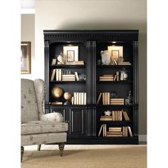 a black bookcase with lots of books on it in front of a gray chair