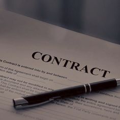 a pen sitting on top of a paper with the word contract written in it's center