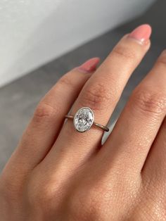 a woman's hand with a diamond ring on her finger and the other hand holding an engagement ring