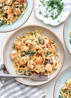 four plates of pasta with shrimp and spinach