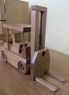 a wooden toy forklift sitting on top of a hard wood floor next to a mirror