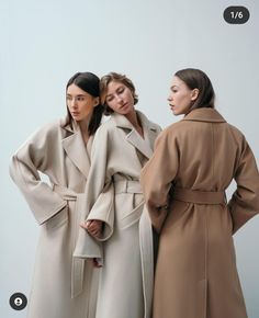 three women standing next to each other in coats