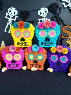 colorful sugar skulls are displayed on a black background with paper flowers in the shape of skull heads