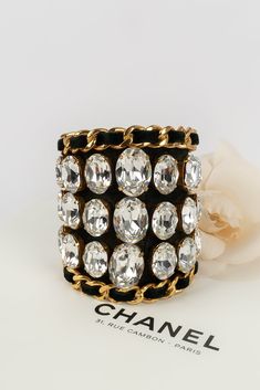 CHANEL -(Made in France) Imposante manchette en cuir noir et métal doré pavé de strass. Collection 2cc6. Condition : Bon état Dimensions : Circonférence : 13 cm - Ouverture : 4 cm - Largeur : 9,5 cm Chanel Cuff Bracelet, Chanel Cuff, Chanel Bracelet, Gold Ounce, Lady Dior, Credit Card Debit, Bracelet Stack, Fendi Bags, Debit Card