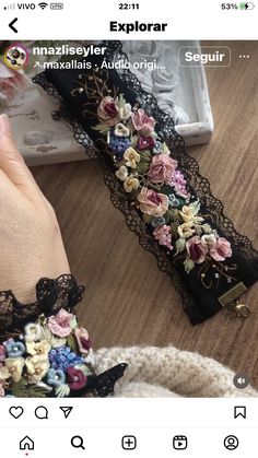 a woman's hand is holding an object with flowers on it and lace around the edges