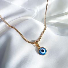 A dainty, modern evil eye necklace crafted to perfection. Made up of 18K gold filled, shimmering white and blue enamel - this necklace has a powerful meaning. Perfect for layering, or wearing on its own, this evil eye necklace will protect you from all.  #Gold #fashion #Jewelry #Necklace #Pendant Do not wear it to the pool, spa, or the beach. - Remove when sleeping or exercising. - Avoid contact with perfumes, body oils and other chemicals, including household cleaners. - Do not use chemical jewelry cleaners. - Gently polish with a soft, lint-free cloth. Please do not use a metal polishing cloth. - Store your jewelry in a cool dry place. Gold-plated Evil Eye Amulet Necklace, Gold Plated Evil Eye Amulet Necklace, Blue Gold-plated Charm Necklace With Adjustable Chain, Blue Gold-plated Chain Necklace As Gift, Blue Gold Plated Chain Necklace As Gift, Blue Dainty Charm Necklaces, Dainty Blue Necklaces With Charms, Blue Adjustable Gold-plated Chain Necklace, Blue Adjustable Gold Plated Chain Necklace