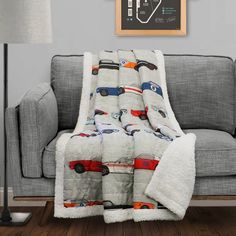 a couch with a blanket that has cars printed on it and is next to a lamp