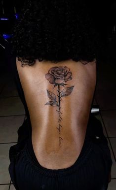 a woman's back with a rose tattoo on it