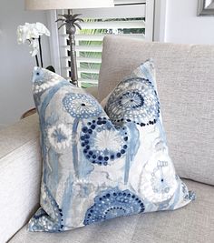 a blue and white pillow sitting on top of a couch next to a lamp in a living room