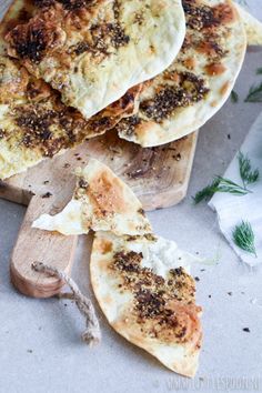 several pieces of flat bread on wooden cutting boards with herbs and seasoning sprinkles