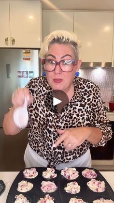 a woman with glasses is making cupcakes in the kitchen