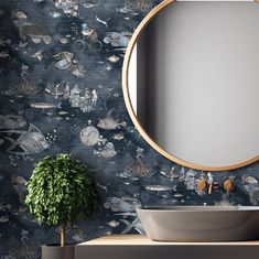 a round mirror on the wall above a sink in front of a blue wallpaper