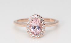 an oval shaped pink sapphire and diamond halo engagement ring in rose gold with white diamonds