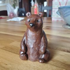 a brown bear figurine sitting on top of a wooden table