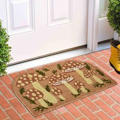 a pair of yellow rubber boots sitting next to a door mat with mushrooms on it