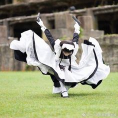 a woman dressed in black and white dancing on grass