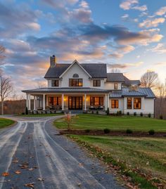 a large white house sitting on the side of a road next to a lush green field