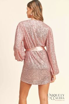 Light up the room with your magnificent self in the Samantha Pink Sequined Long Sleeve Wrap Dress! Sparkly pink sequins (atop gauzy beige woven fabric) dazzle across a wrapping bodice (that secures with a hidden snap and two internal ties) and long sleeves with gathered shoulders and elastic cuffs. Matching satin sash belt cinches the waist above a wrap mini skirt. - Lined - Dress: 50% PET, and 50% Polyester - Lining: 100% Polyester - Fits True To Size (S: 2-4, M: 6-8, L:10-12) - Hand Wash Cold. Pink Shimmer Sequin Dress For Night Out, Glamorous Sequin Dress With Surplice Neckline, Sequin Surplice Neckline Dress For Party Season, Cocktail Dress With Sequins And Surplice Neckline, Sequin Dress With Surplice Neckline For Date Night, Sequin Surplice Neckline Dress For Date Night, Chic Surplice Neckline Dress With Sequins, Pink Embellished V-neck Sequin Dress, Glamorous Pink Shimmer Sequin Dress