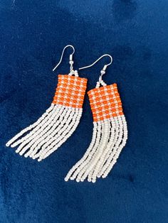 The perfect accessory for all of UTK Vol Fans out there OR anyone that loves Orange (it's my fav color!)  These earrings are hand stitched with high quality seed beads into an orange gingham pattern with a cream hinge. These earrings will help share your love for UTK; however they are understated making them perfect for everyday wear. These are part of my UTK VOL Collection you can find on my Etsy page. Product Features * 3" long x .75" wide * Handmade * Lightweight * Glass Sead Beads. * Stainless steel hook. Nickel free. These make lovely gifts for yourself or anyone who loves the VOLS! Care Instructions:  - To clean: Wipe with a microfiber cloth to remove any dust - Avoid contact with perfumes and lotions as these can react with acrylic and cause discoloration in some cases. We recommend Handmade White Beaded Rectangular Earrings, Handmade White Rectangular Beaded Earrings, Orange Gingham, Fringe Earring, Fav Color, Opening An Etsy Shop, Seed Beading, Gingham Pattern, University Of Tennessee