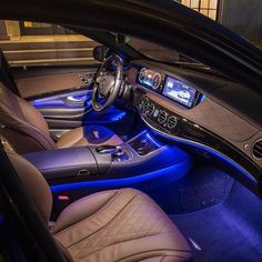 the interior of a car is lit up with blue lights and black leather trims