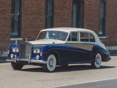 an old blue and white car parked in front of a brick building