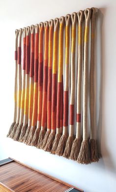 a wall hanging made out of different colored yarns and tassels on a white wall