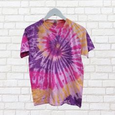 Go retro with our pink, purple and yellow tie dye t-shirt! Made from sustainable cotton and dyed with eco-reactive dyes, this pastel shirt is as environmentally conscious as it is stylish. Perfect for adding a pop of color to any outfit.  (No boring tees here!) Relaxed Fit Tie-dye T-shirt With Natural Dye, Purple Hand Dyed Tops For Spring, Tie-dye Cotton T-shirt For Spring, Spring Tie-dye Cotton T-shirt, Hand Dyed Pink Short Sleeve Tops, Pink Hand Dyed Short Sleeve Tops, Hand Dyed Rainbow Tops For Spring, Pink Hand Dyed Cotton Top, Summer Tie-dye T-shirt With Natural Dye