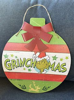 a christmas ornament hanging on the back of a couch with a red bow