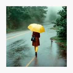 a woman walking down the road in the rain with an umbrella